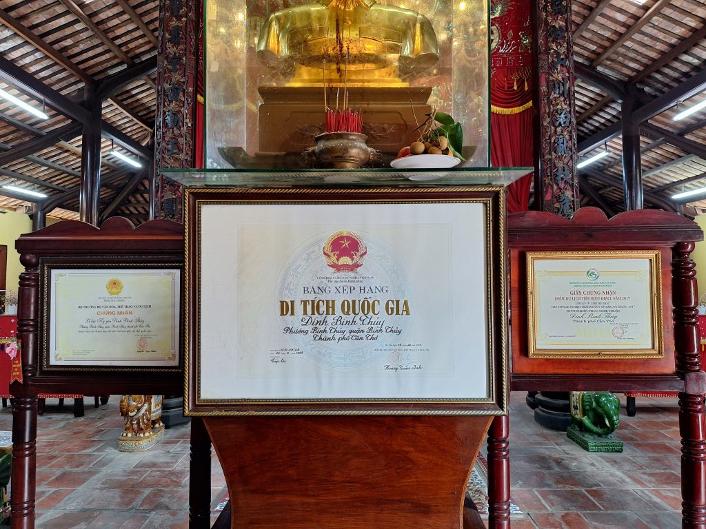 Khung kính trang trọng đặt Bằng xếp hạng Di tích quốc gia Đình Bình Thủy thuộc tỉnh Cần Thơ cũ bên trong không gian thờ tự gian chính điện.